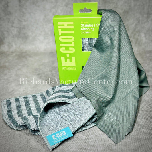 The image shows a stainless steel cleaning kit which includes a striped stainless steel cleaning cloth, a solid glass & polishing cloth, and their packaging with branding visible.