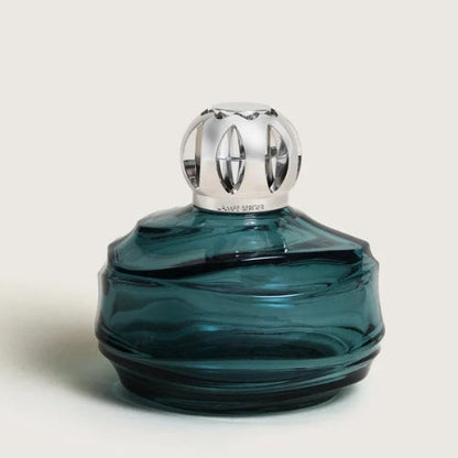 A dark teal blue glass bottle with a polished silver diffuser cap.