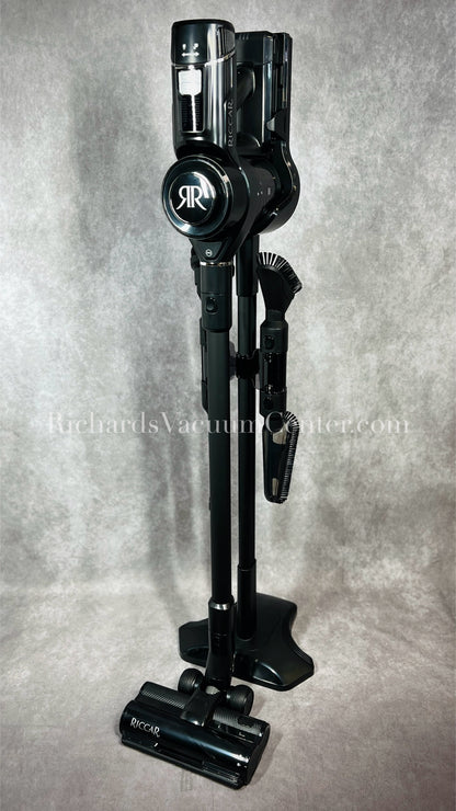 Black vacuum cleaner with attachments on a gray background